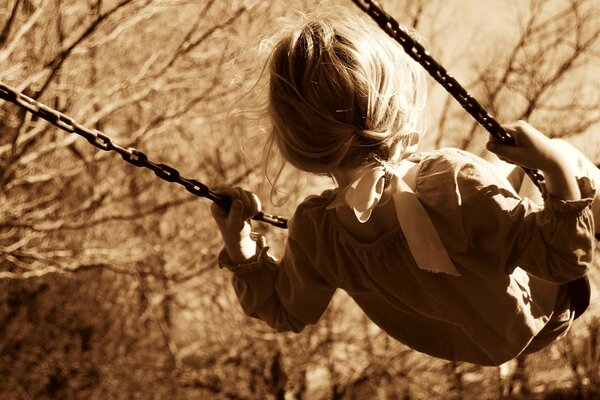 A girl with a bow swings on a swing