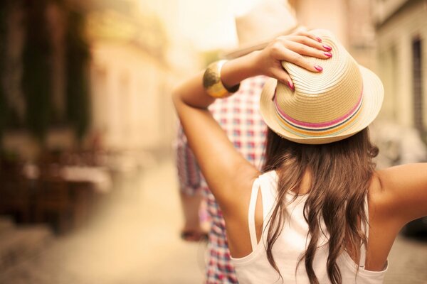 A girl in a white T-shirt holds her hat