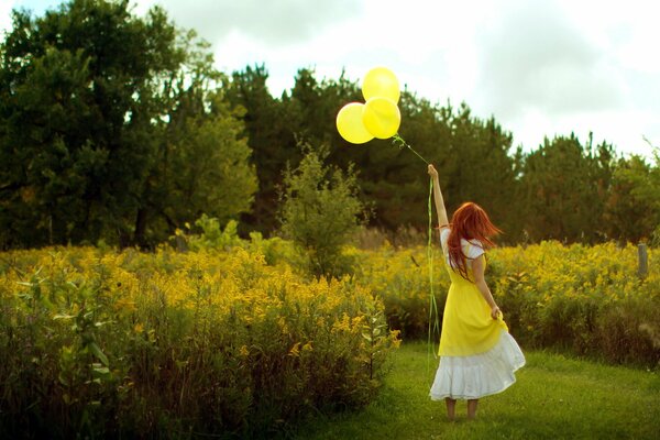 A red-haired girl in a white and yellow dress with yellow balls on a field with tall yellow flowers