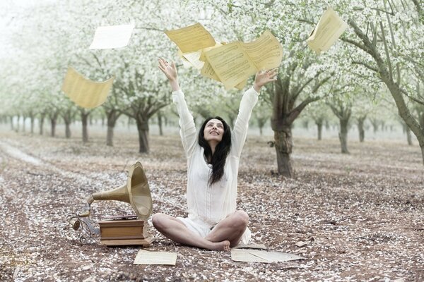 A girl throws notes next to a gramophone in the garden