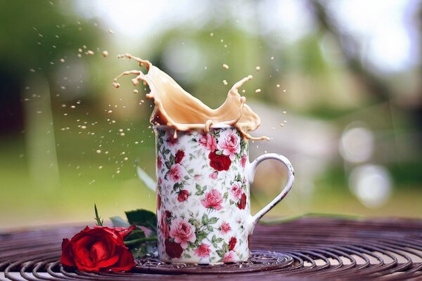 Composizione di rosa rossa e tazza con spruzzi di caffè