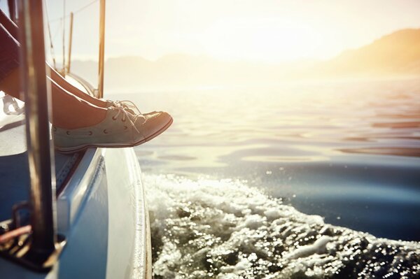 Weibliche Füße in blauen Schuhen auf einer Yacht