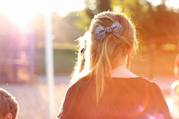 Hairstyle of a girl with a bow in the sun