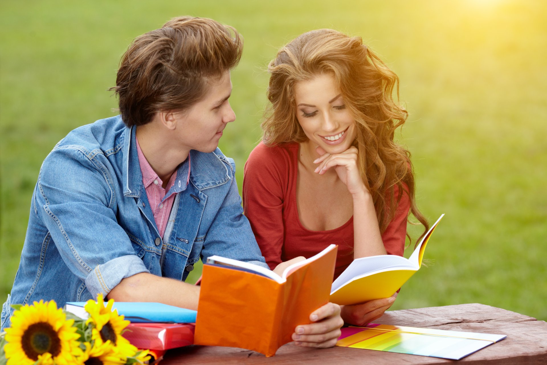 ragazza capelli castani riccioli ragazzo sorrisi quaderni erba parco giornata di sole girasoli