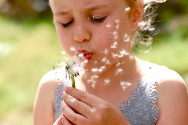 Ragazza seria che soffia il dente di leone