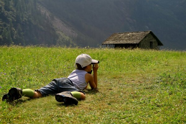 Junge, der ein Haus im Gras beobachtet