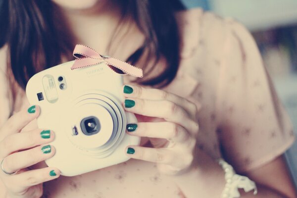 Macchina fotografica nelle mani di una ragazza con le unghie verdi