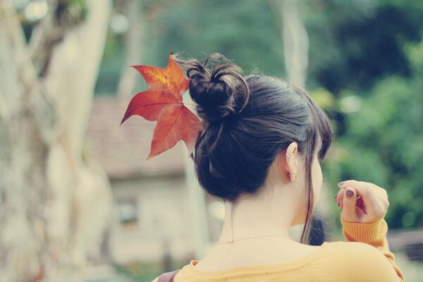 Fille dans un pull jaune avec une feuille dans les cheveux