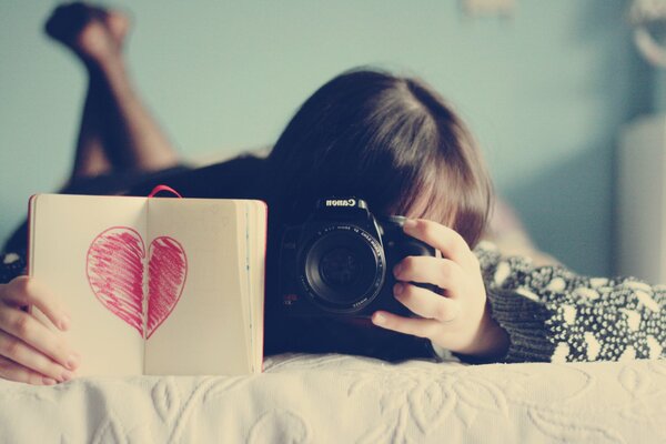 A girl takes pictures of a notebook with a picture of a heart