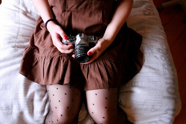 The girl is sitting with a photo camera in her hands