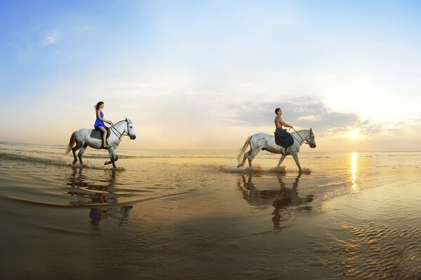 Lovers horseback ride along the seashore