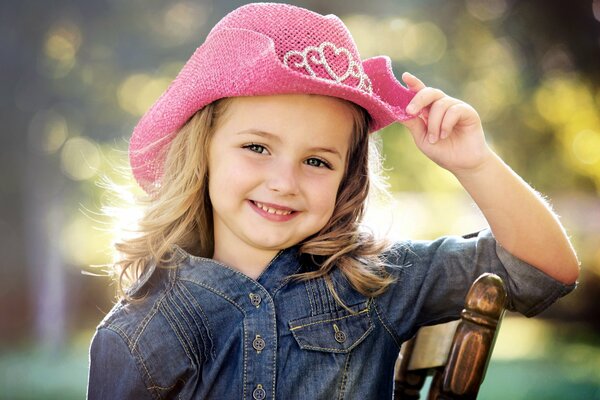 Linda chica sonriente con camisa de mezclilla y sombrero de vaquero rosa