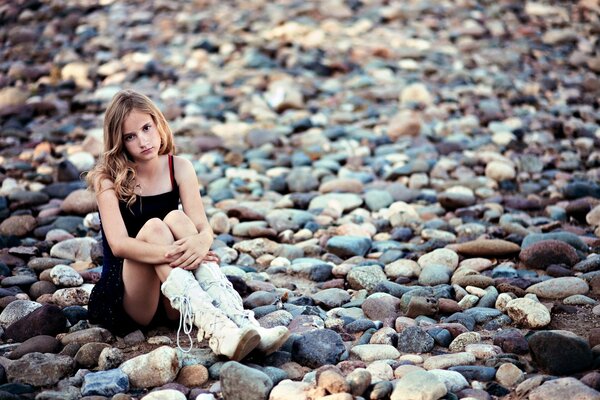 Chica seria sentada en las rocas