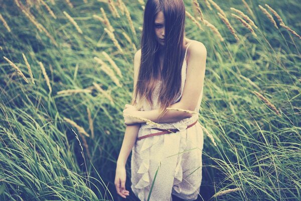 A girl with loose hair stands in a field