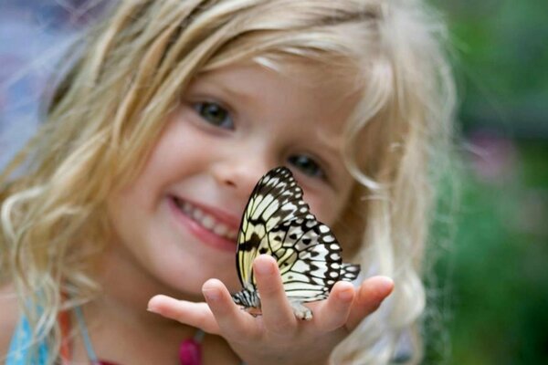 Lockiges Mädchen freut sich über einen Schmetterling