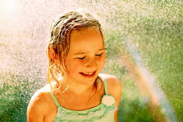 Freudiges Mädchen in Wassertropfen und Regenbogen