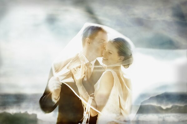 The bride and groom under a white veil