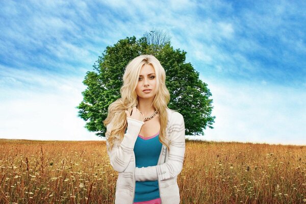 Blonde debout dans la Prairie sur fond d arbre solitaire et le ciel bleu