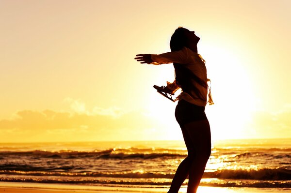 Silueta de una chica alegre en el fondo de una puesta de sol del mar