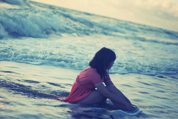 The girl is sitting in the sea and enjoying the sea water