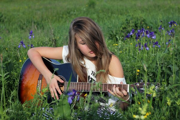 A girl with a guitar in a summer glade