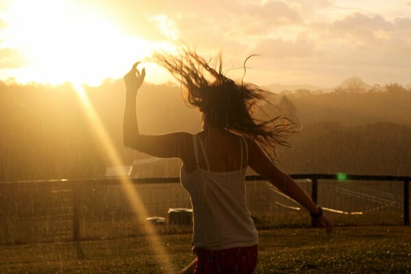 La chica corriendo al encuentro del sol bajo la lluvia