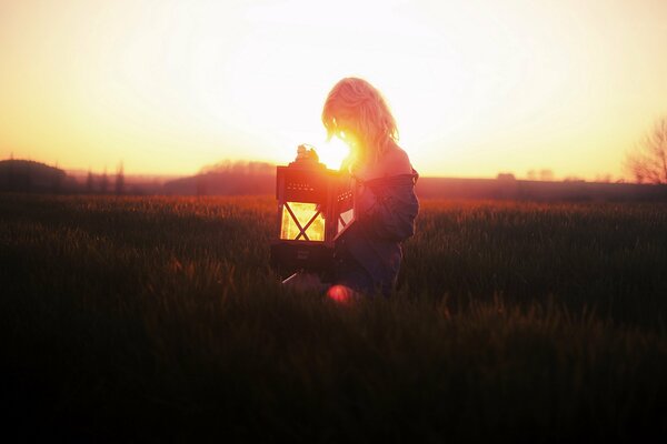 Jeune fille dans un champ avec une lampe au coucher du soleil