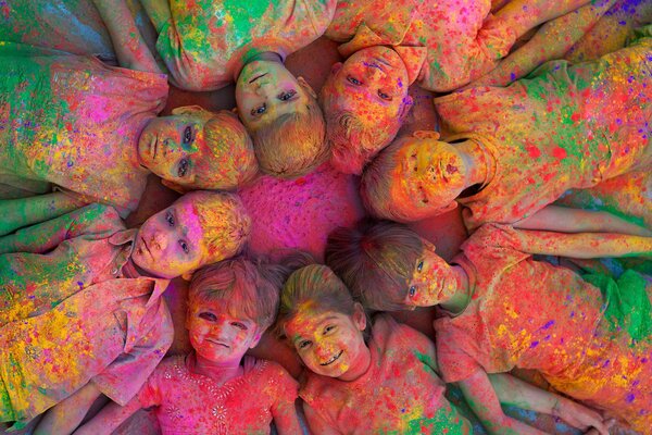 Los niños pintados de colores se encuentran sol jugando