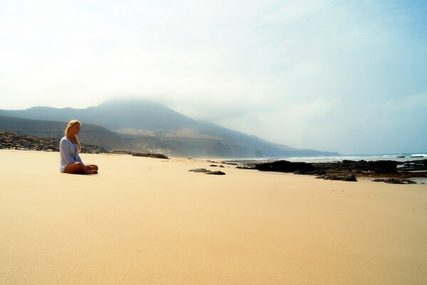 Fille assise seule sur la plage de sable