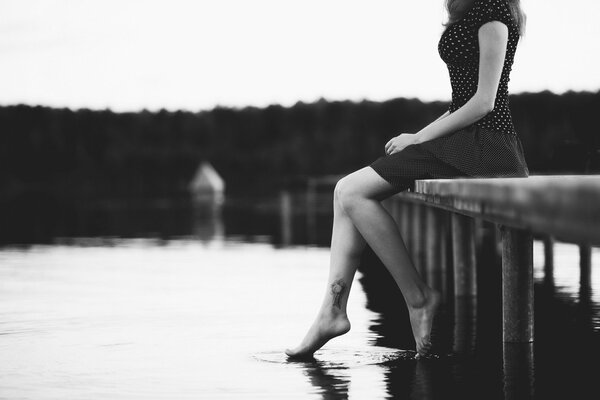 A girl looking thoughtfully at the water on a black and white background