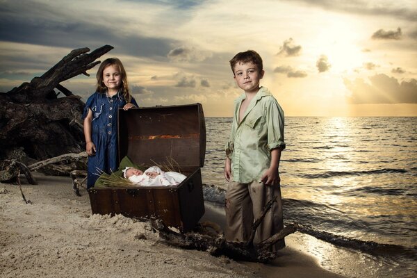 Bruder und Schwester werden mit einem neugeborenen Kind am Meer fotografiert