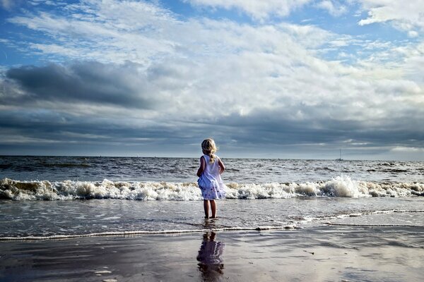 Niña en el mar en las nubes de reflexión