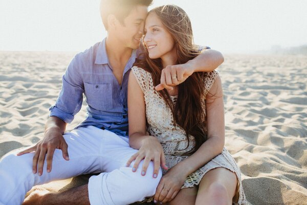 Guy et fille assis sur le sable