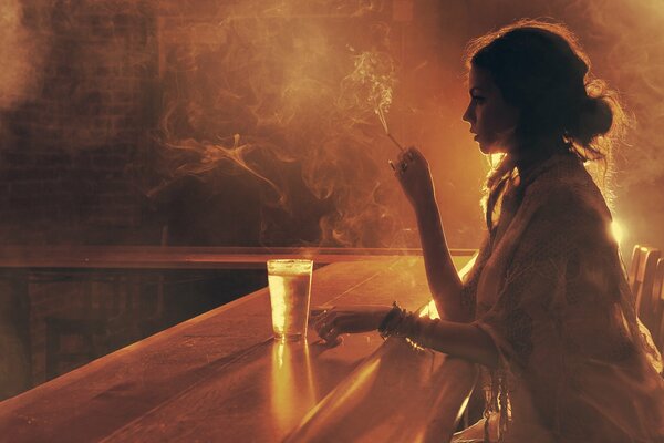 A girl sitting alone in a bar smoking a cigarette