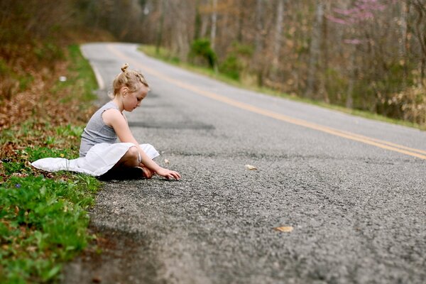 The girl is sitting on the road