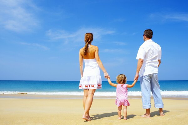 Trio de famille sur une plaque de sable, main dans la main