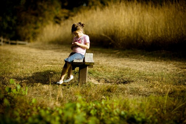 A girl in nature is sitting on a bench