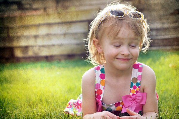 A smiling girl with her eyes closed is lying on the grass