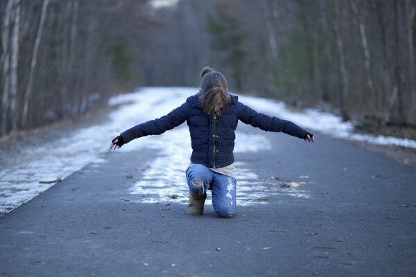 La ragazza si siede sulla strada innevata