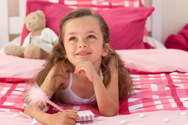 Fille rêveuse avec un ours en Peluche et un bloc-notes