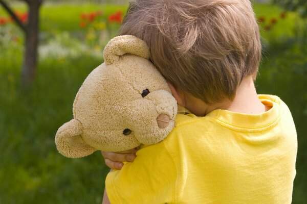 Petit garçon avec un ours en peluche triste