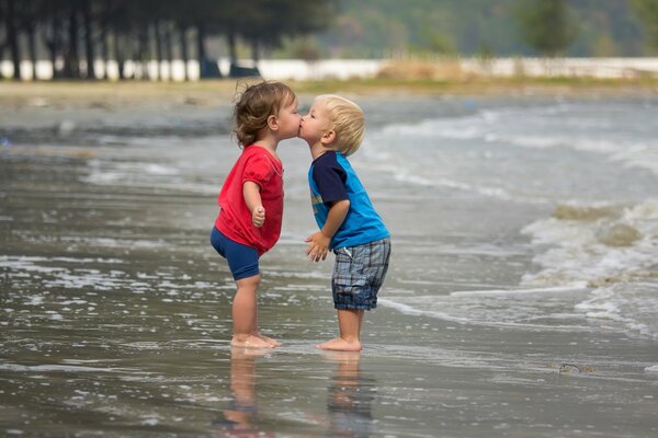 Cute kiss of a boy and a girl on the beach