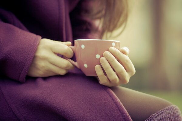 Fille réchauffe les doigts de la main sur une tasse de gros plan chaud