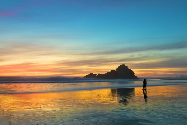 Al atardecer, una pareja de enamorados camina en la playa