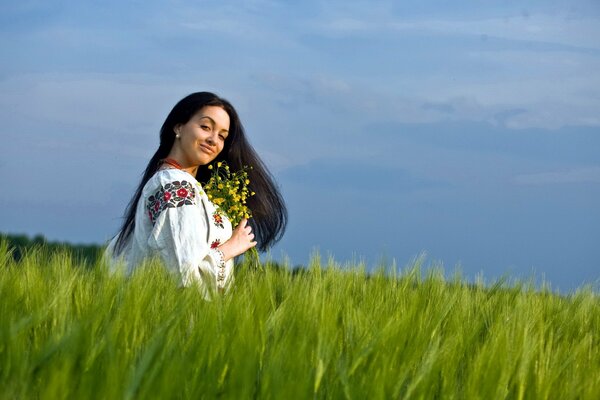 Mädchen sitzt im Gras mit Blumen in ihren Händen