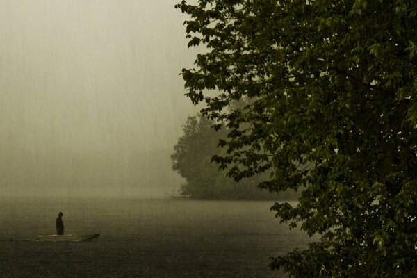 Silhouette in a boat on the lake on a rainy evening