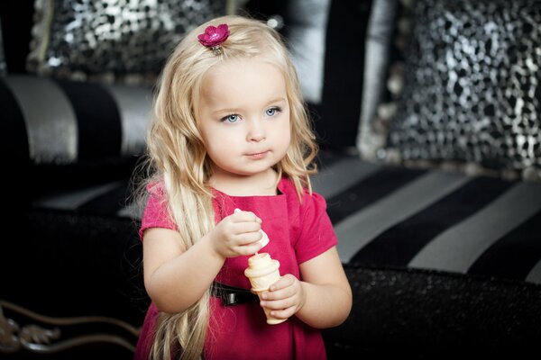 A girl in a pink dress eats ice cream