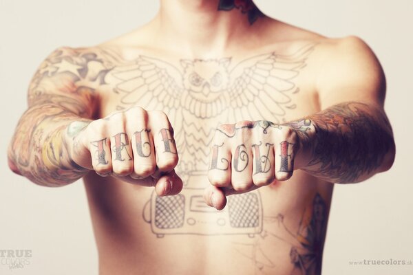 A man with a naked torso on his hands tattooed true love