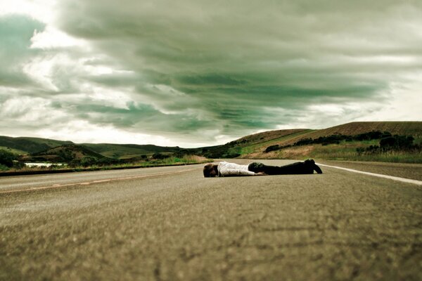 A sad girl is lying on the asphalt