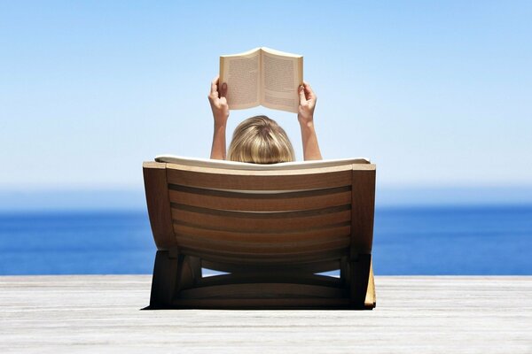 A girl on vacation by the sea with a book